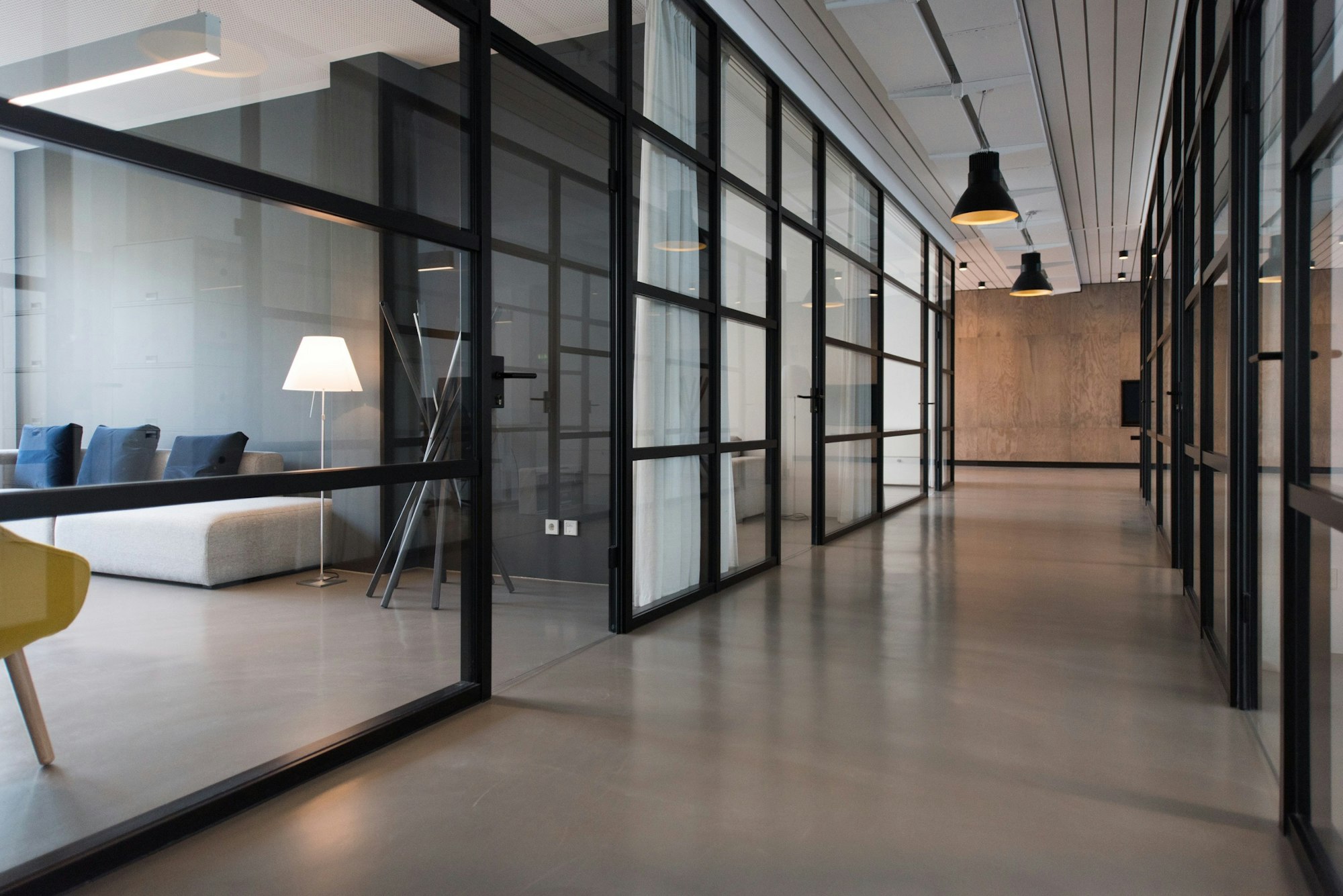 Glass-partitioned office corridor, lit low